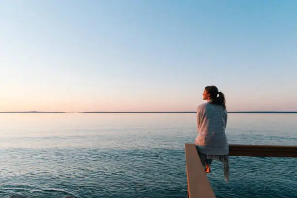 Woman sitting near water looking at the skyline